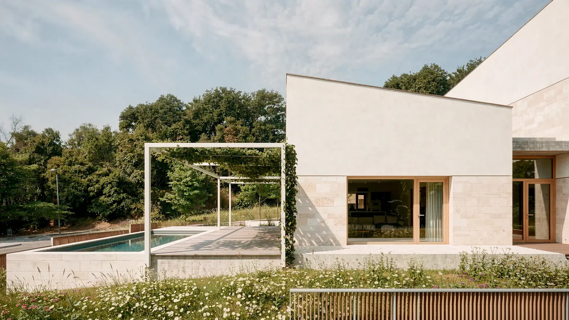 Zona de piscina de vivienda unifamiliar de obra nueva en L'Ametlla del Vallès, con fachada de piedra natural, pérgola metálica, tarima de madera y jardín de pradera silvestre. Proyecto de Tova Arquitectura